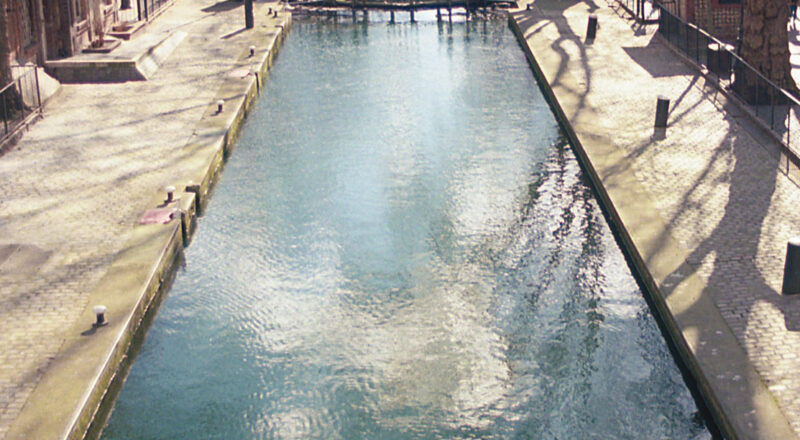 A photograph of a canal in Paris and bridges in the background.