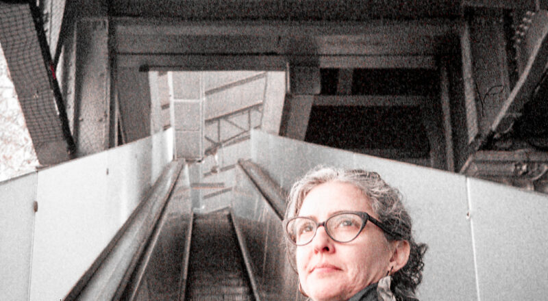 A photograph of a woman on an escalator leading to the Metro in Paris. Taken with a Nikon L35AF and Fujicolor 400 film.