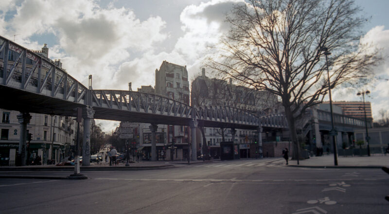 A photograph of a cloudy sky with sun in the background and elevated Metro tracks in the foreground.