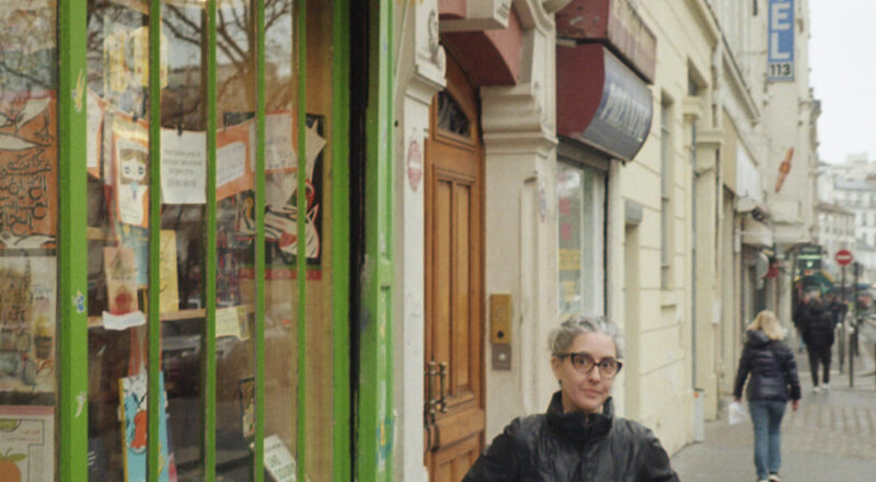 A woman stands out front of a book store on Boulevard Belleville.