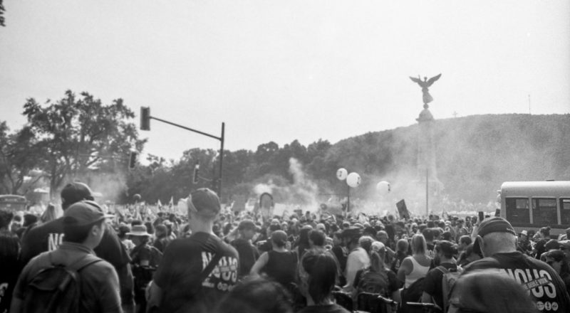 A photograph of protestors and smoke from a union rally in support of Quebec service workers including teachers and nurses near the Sir George-Etienne Cartier Monument in Montreal during the summer of 2023. Taken with a Canon F1New using CatLabs 320 film.