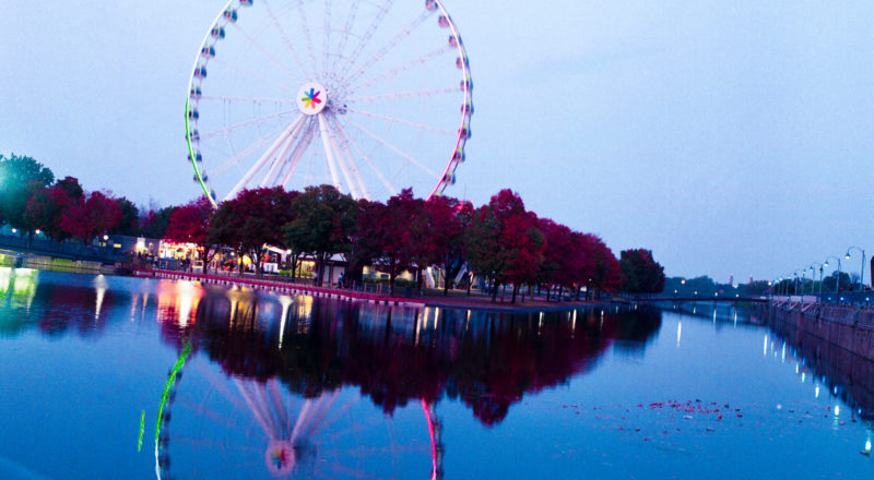 Montreal's Old Port and the ferris wheel reflected in the pond, photographed at the golden hour using a Mamiya M645 1000S and Portra 800 film.