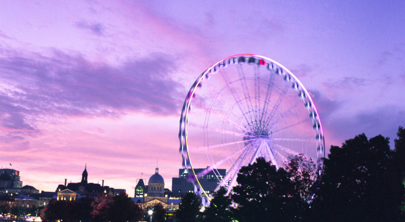 Montreal's Old Port and the ferris wheel photographed at the golden hour with a dramatic sky in the background using a Mamiya M645 1000S and Portra 800 film.